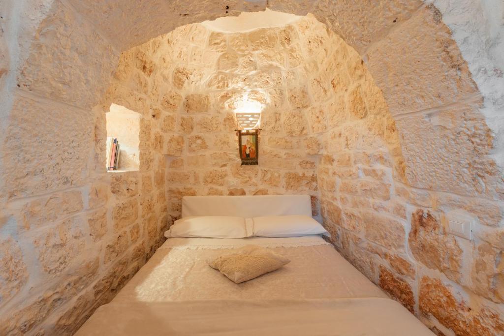 Cette petite chambre comprend un lit dans un mur en pierre. dans l'établissement Trullo Milù with Pool, à San Michele Salentino 18 autres photos