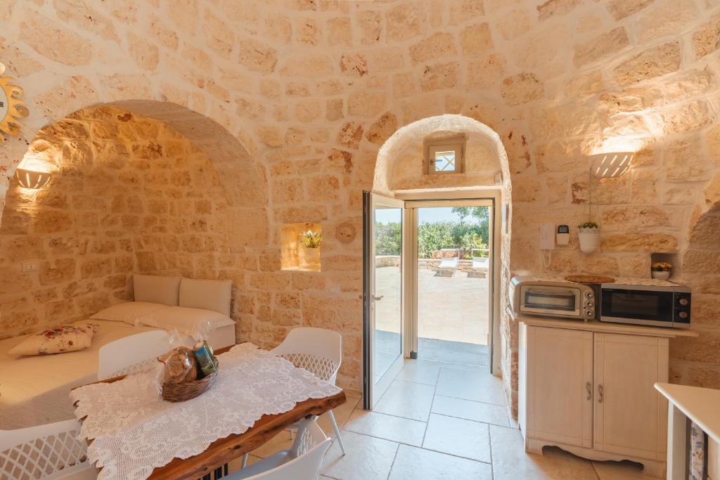 une cuisine et un salon dans une maison en pierre avec une table dans l'établissement Trullo Milù with Pool, à San Michele Salentino