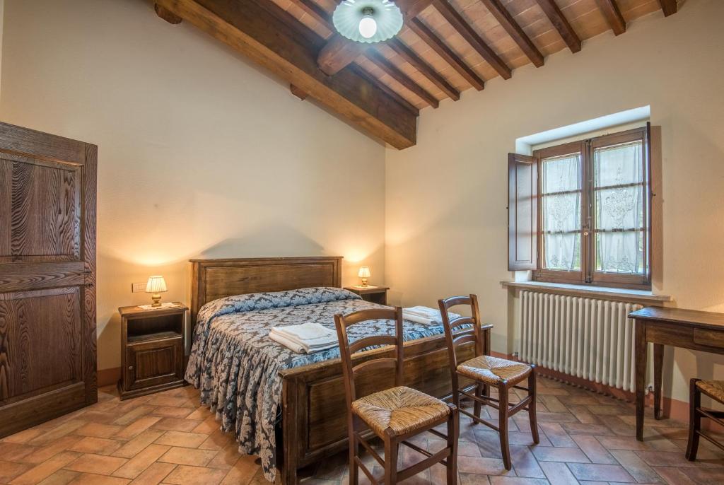 une chambre avec un lit, deux chaises et une table dans l'établissement Villa Agriturismo Il Pratone, à Castiglione dʼOrcia 15 autres photos
