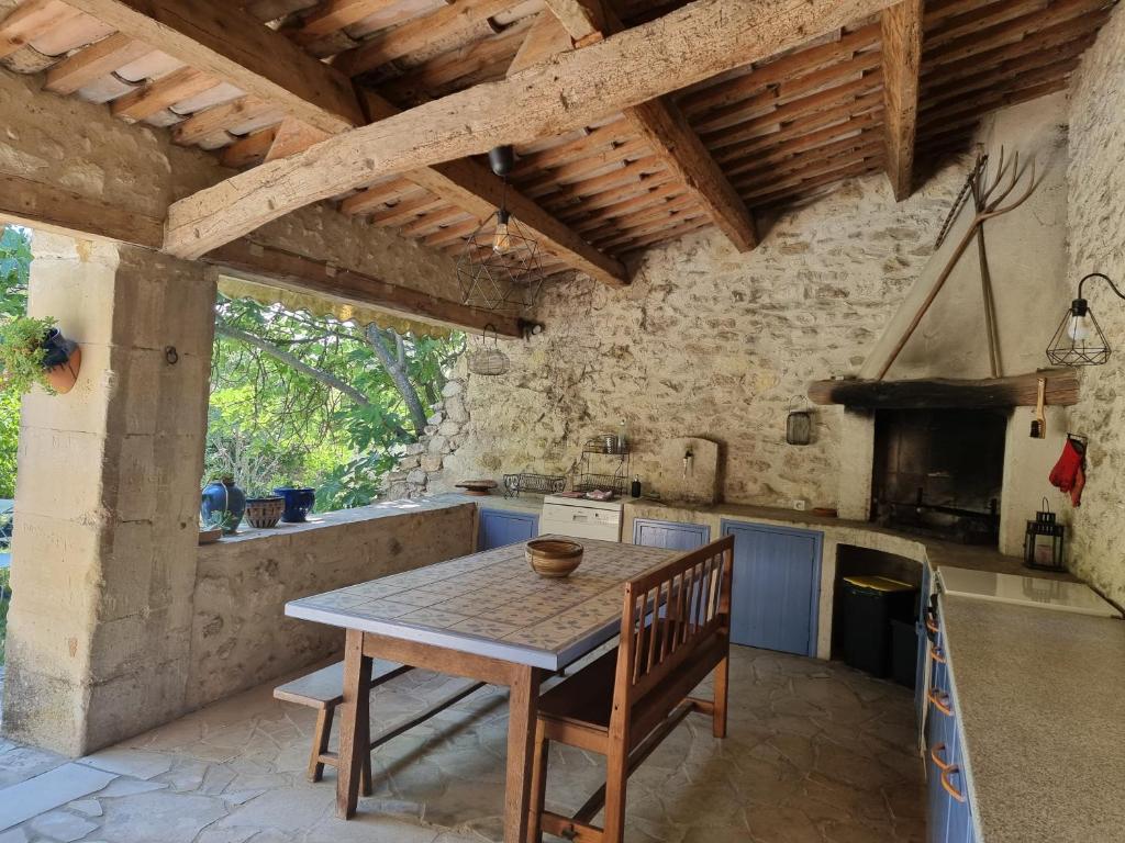 une cuisine avec une table en bois et une table et des chaises dans l'établissement Le Pigeonnier, gîte des Lucioles en Provence, à Montségur-sur-Lauzon