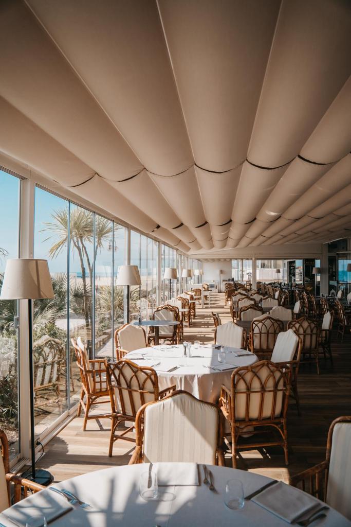 une salle à manger avec tables, chaises et fenêtres dans l'établissement Hotel Villa Sorriso, à Lido di Jesolo