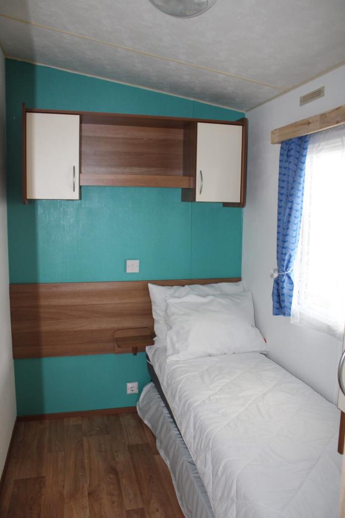 - une petite chambre avec un lit et un mur bleu dans l'établissement Mobil-home spatieux 8pers - BRUME, à Saint-Julien-en-Born 6 autres photos