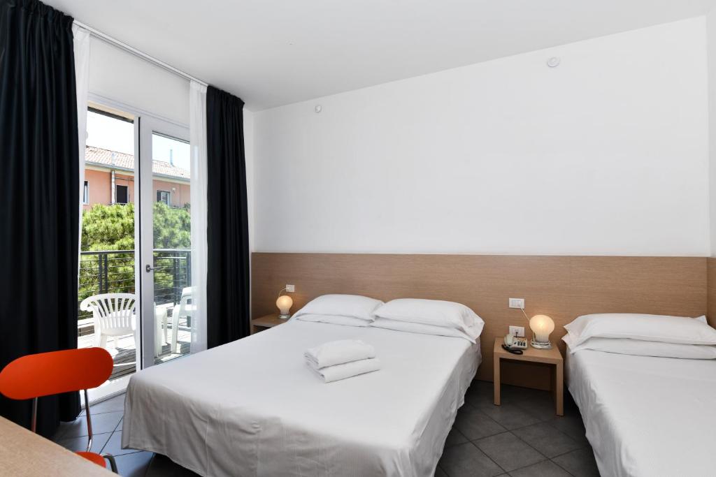 une chambre d'hôtel avec deux lits et un balcon dans l'établissement Hotel Eden, à Lido di Jesolo