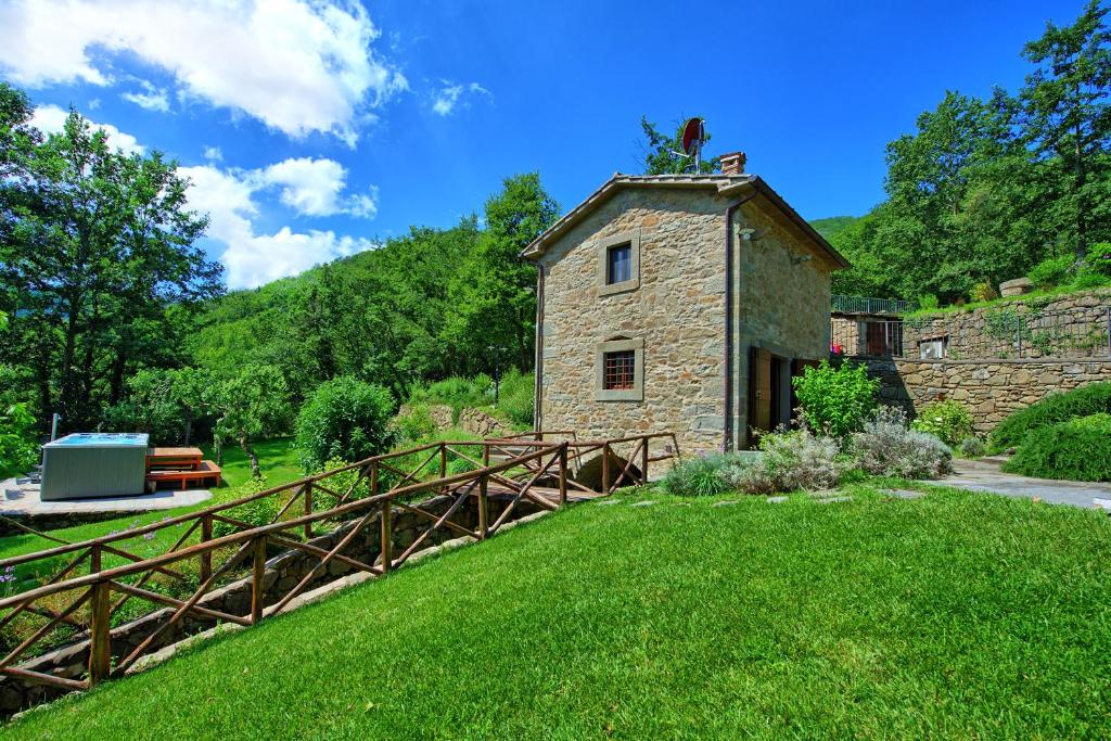 - un vieux bâtiment en pierre avec un pont en bois dans l'établissement Villa Mulino by PosarelliVillas, à Poggioni
