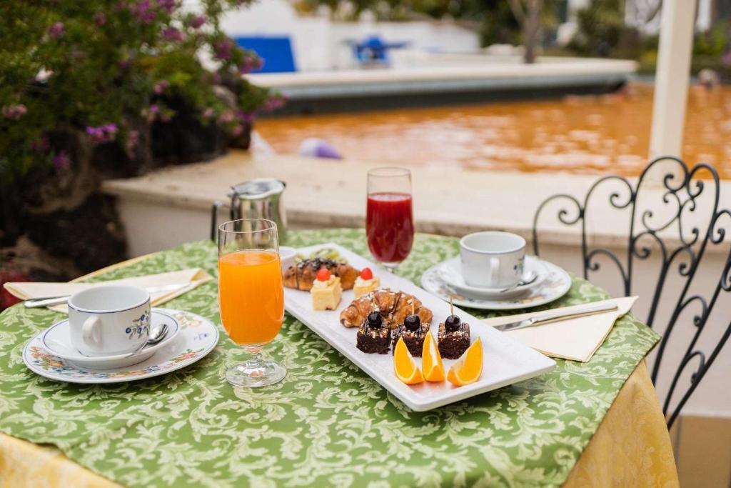 une table avec une assiette de nourriture et deux verres de jus d'orange dans l'établissement Hotel Royal Terme, à Ischia