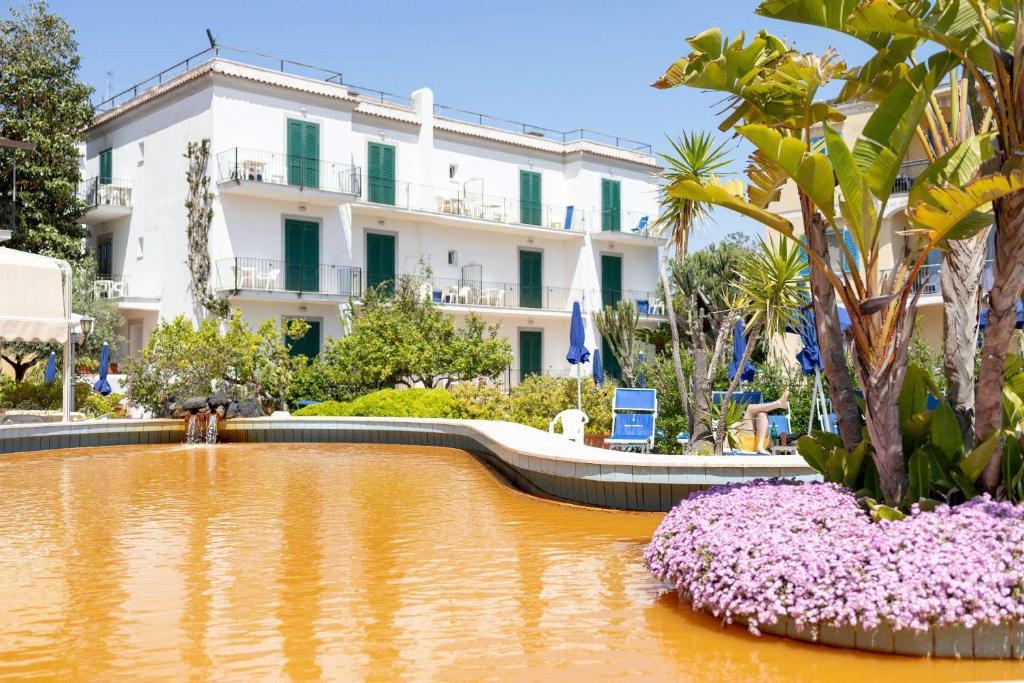 un grand bâtiment avec un étang en face dans l'établissement Hotel Royal Terme, à Ischia