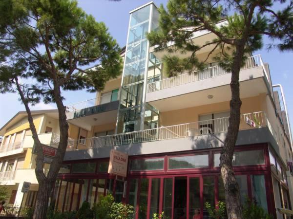 un grand bâtiment avec des arbres devant dans l'établissement Hotel Villa Dina, à Lido di Jesolo