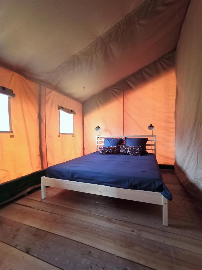 une chambre avec un lit dans une tente dans l'établissement Le Lodge de la Chouette, à Quarré-les-Tombes