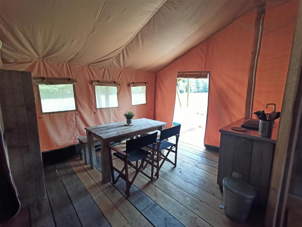 une table dans une tente avec des chaises dans une pièce dans l'établissement Le Lodge de la Chouette, à Quarré-les-Tombes