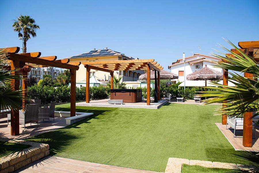 une cour arrière avec une pelouse et une pergola en bois dans l'établissement Hotel Acquario, à Campomarino