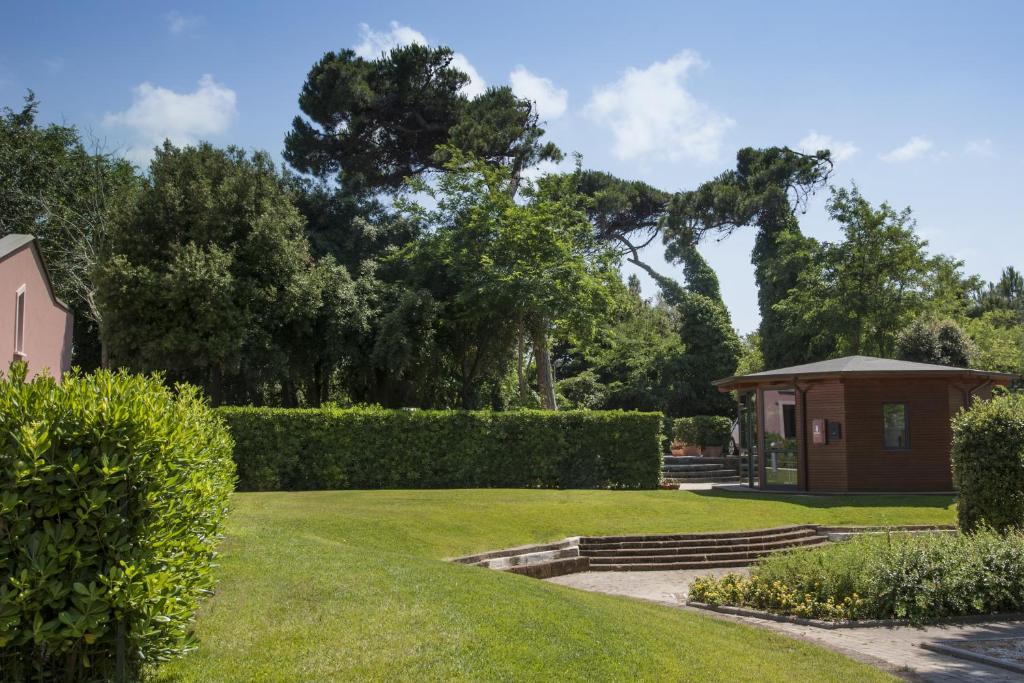 un jardin avec un petit bâtiment et des arbres dans l'établissement Miramare Resort, à Tirrenia