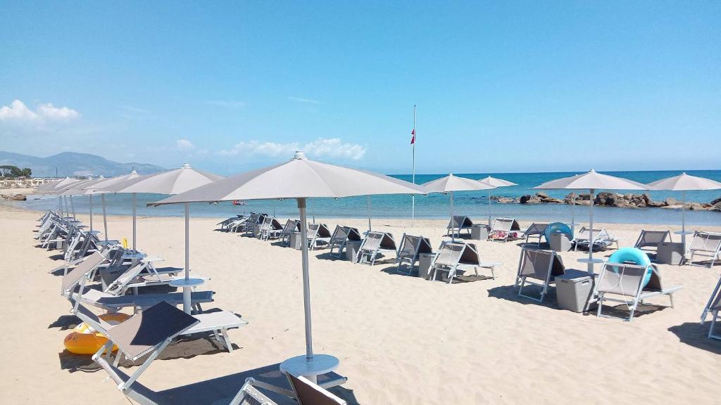 un groupe de chaises et de parasols sur une plage dans l'établissement Hotel Mercede 2, à San Felice Circeo