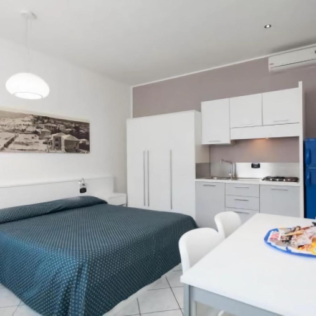 Cet appartement comprend une chambre avec un lit et une cuisine blanche. dans l'établissement Hotel & Residence Progresso, à Lido di Jesolo