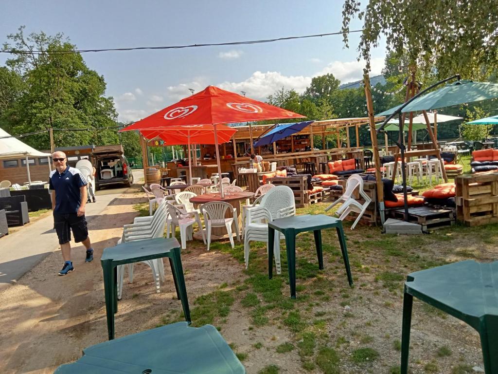 un homme debout devant les tables et les chaises dans l'établissement mobil-home du lac de Foix, à Foix