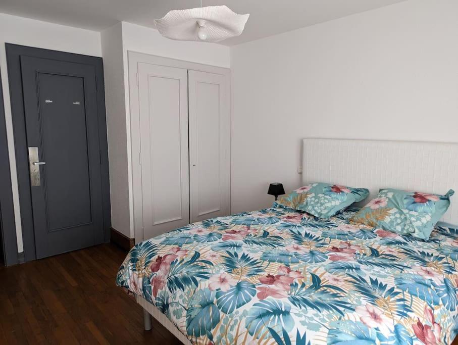 une chambre avec un lit avec un couvre-lit fleuri dans l'établissement appartement plein centre Saint die des Vosges, à Saint-Dié-des-Vosges