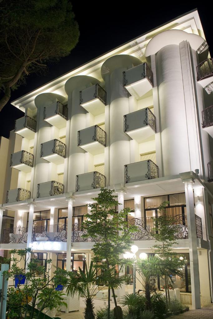 - un grand bâtiment blanc avec balcon la nuit dans l'établissement Hotel Baby B&B, à Milano Marittima