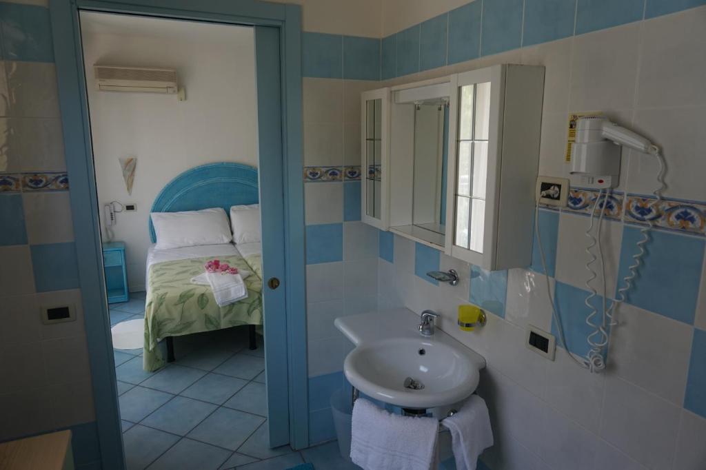une salle de bain avec un lavabo et un lit dans l'établissement Hotel Da Giovanna, à Lignano Sabbiadoro