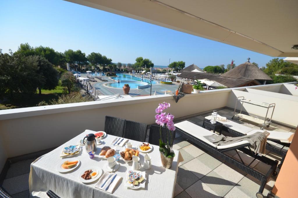 - une table avec de la nourriture sur un balcon avec vue sur la piscine dans l'établissement Aparthotel Holiday, à Bibione
