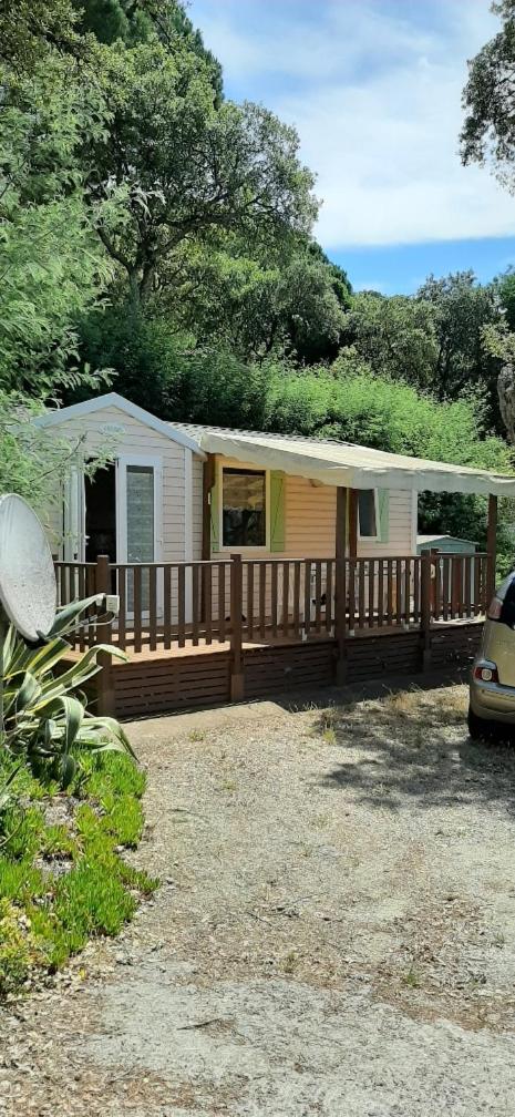 une petite maison avec une terrasse couverte et une clôture dans l'établissement mobil home Gassin, à Gassin