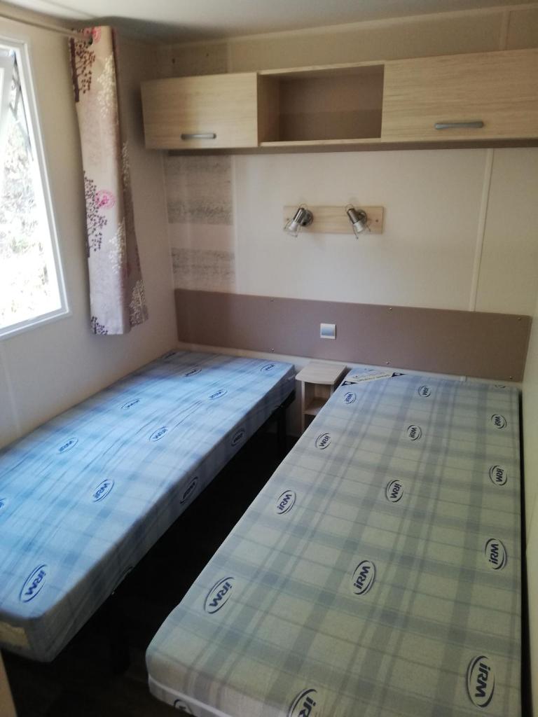 deux lits dans une petite pièce avec une fenêtre dans l'établissement mobil home Gassin, à Gassin