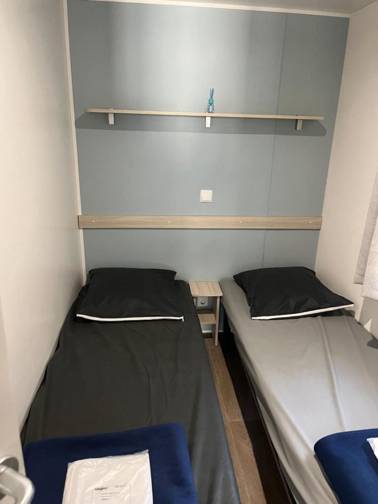 - 2 lits dans une petite chambre avec des étagères dans l'établissement Camping la Marine, au Grau-du-Roi