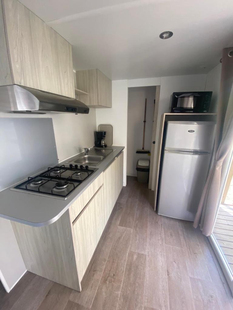 Il comprend une petite cuisine équipée d'une cuisinière et d'un réfrigérateur. dans l'établissement Mobil Home 4 personnes, à Narbonne-Plage