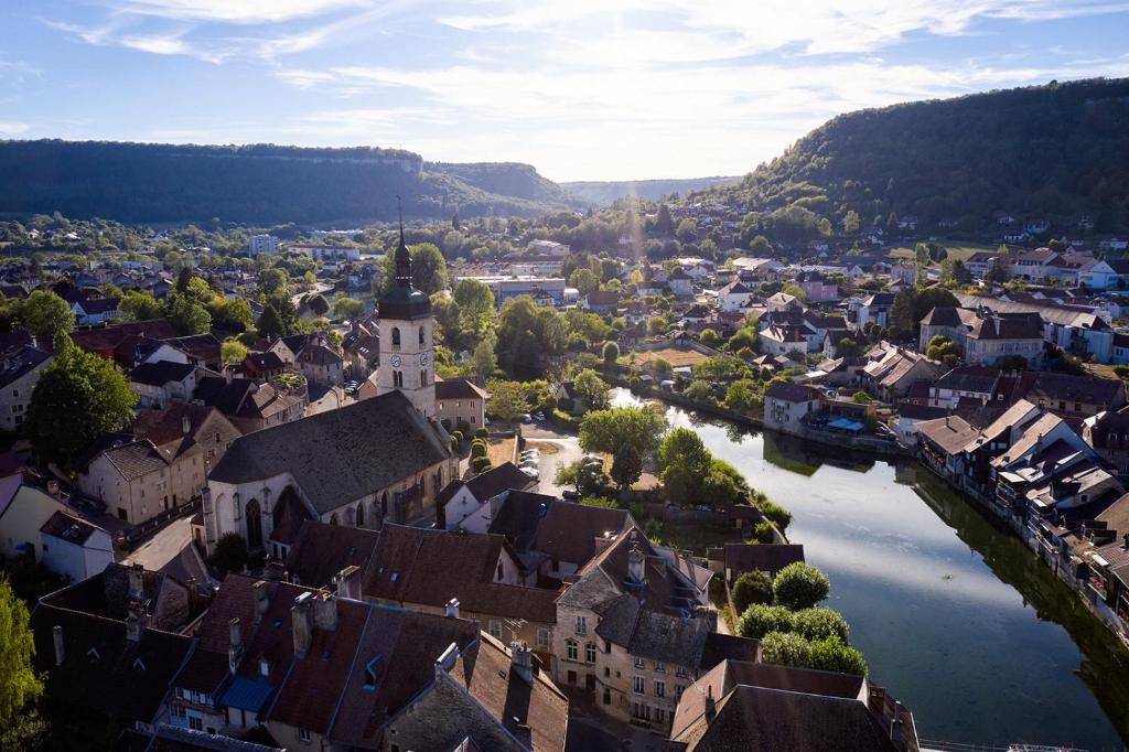 une vue aérienne sur une ville avec une rivière dans l'établissement Glamping Ornans, à Ornans