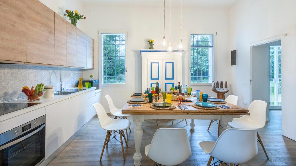 - une cuisine avec une table en bois et des chaises blanches dans l'établissement VILLA RUSTICA 8, Emma Villas, à San Pietro in Vincoli