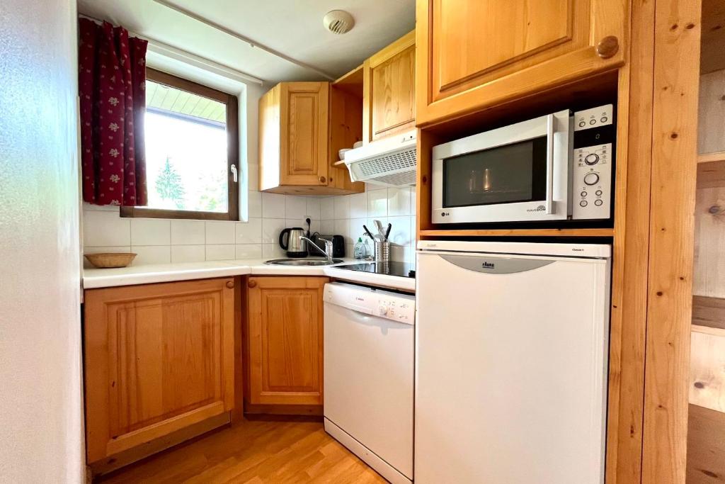 La cuisine est équipée d'un réfrigérateur blanc et d'un four micro-ondes. dans l'établissement Bright 50 m cocoon with balcony in Combloux, à Combloux