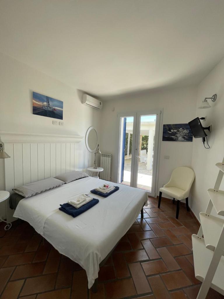 une chambre avec un grand lit blanc et une chaise dans l'établissement Villa Krailo, à Santa Maria al Bagno 30 autres photos