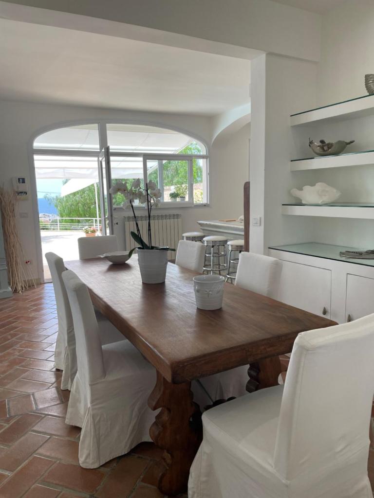 une salle à manger avec une table en bois et des chaises blanches dans l'établissement Villa Krailo, à Santa Maria al Bagno