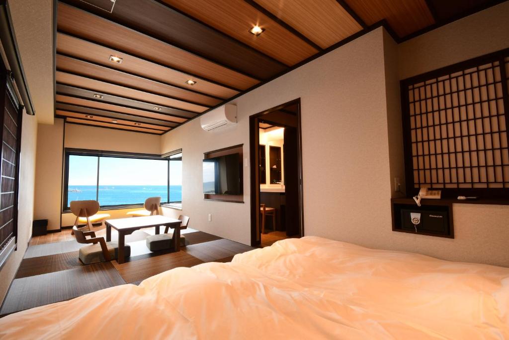 une chambre avec un lit, une table et des chaises dans l'établissement 黒潮の宿 臨海荘 -Kuroshio no yado Rinkaisou-, à Katsuura