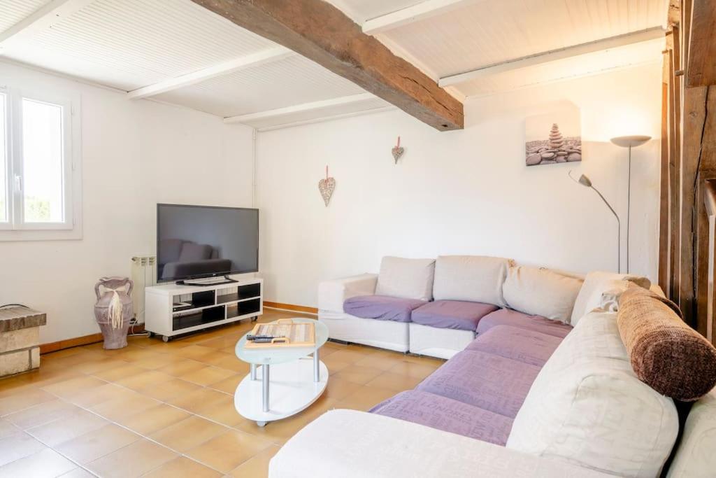 un salon avec un canapé blanc et une télévision dans l'établissement Gîte Le Campane - Piscine partagée Borne recharge véhicule 22kwh, à Laujuzan