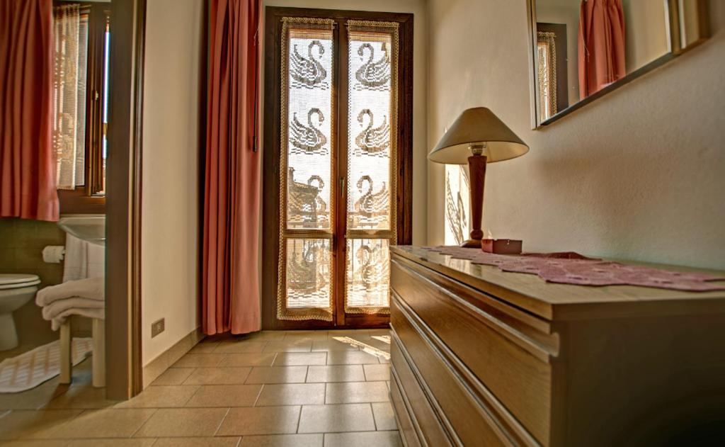 La salle de bains est pourvue d'une commode et d'une fenêtre avec une lampe. dans l'établissement Albergo Casa Este, à Brenzone