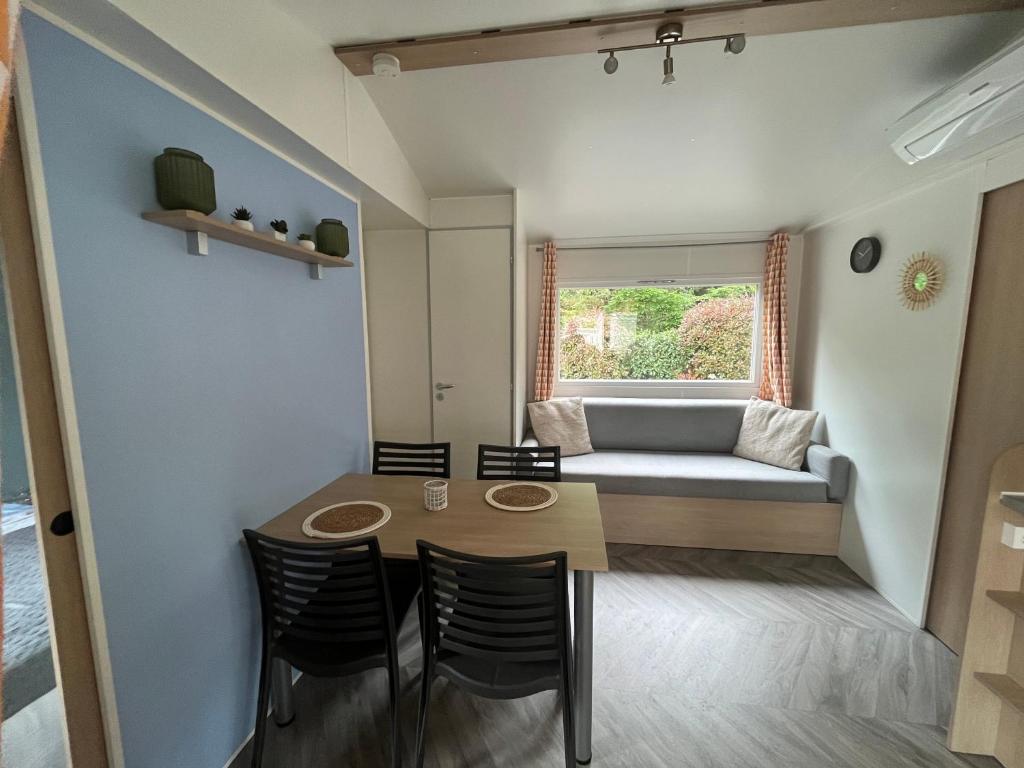 Cette petite chambre comprend une table, des chaises et un canapé. dans l'établissement Mobil home climatisé, à Lège-Cap-Ferret