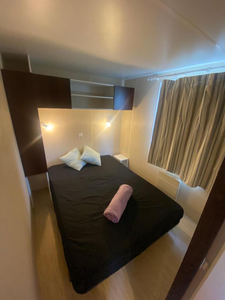 - une petite chambre avec un lit noir et un oreiller rose dans l'établissement Séjour inoubliable en Provence, camping 4*, à La Roque-dʼAnthéron