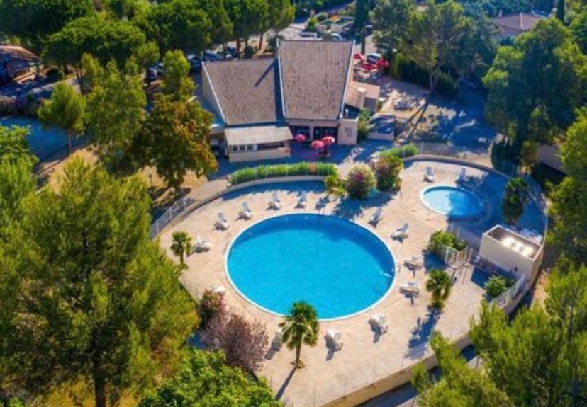 une vue aérienne d'une grande piscine avec des chaises et des arbres dans l'établissement Séjour inoubliable en Provence, camping 4*, à La Roque-dʼAnthéron