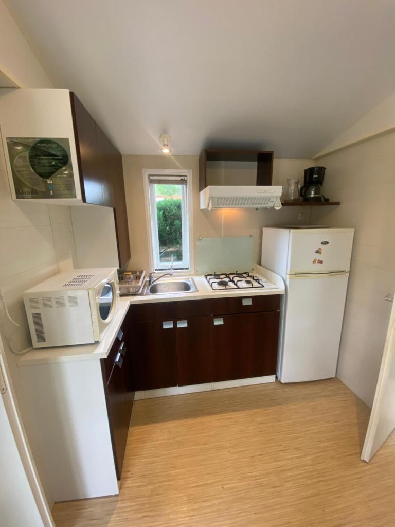 une petite cuisine avec un évier et un micro-ondes dans l'établissement Séjour inoubliable en Provence, camping 4*, à La Roque-dʼAnthéron