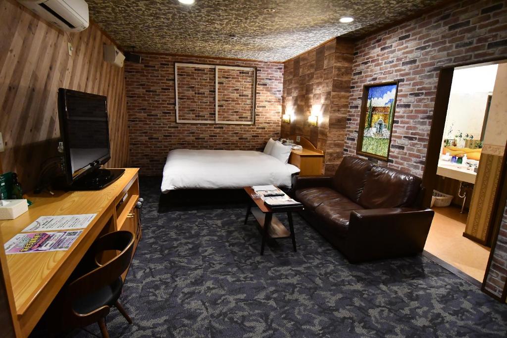 une chambre d'hôtel avec un lit et un canapé dans l'établissement Hotel DOLPHIA-Adult Only, à Daisen