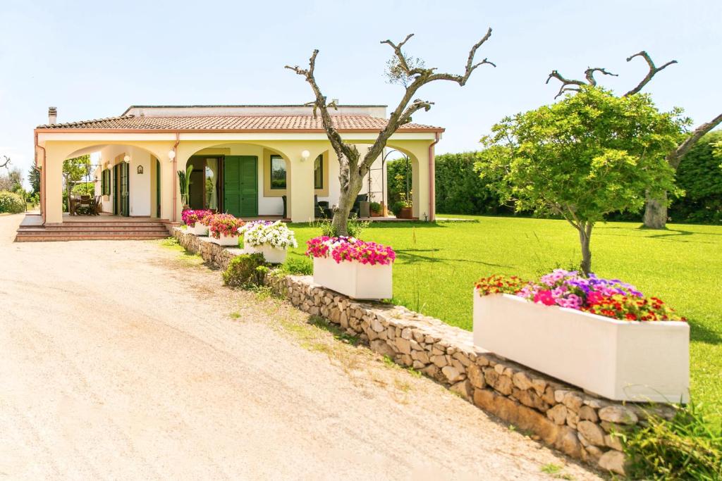 une maison fleurie en face d'une allée. dans l'établissement Podere Corda di Lana, à Leverano