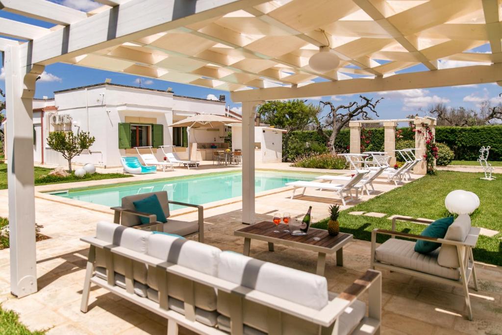 une cour avec une piscine et une pergola blanche dans l'établissement Podere Corda di Lana, à Leverano