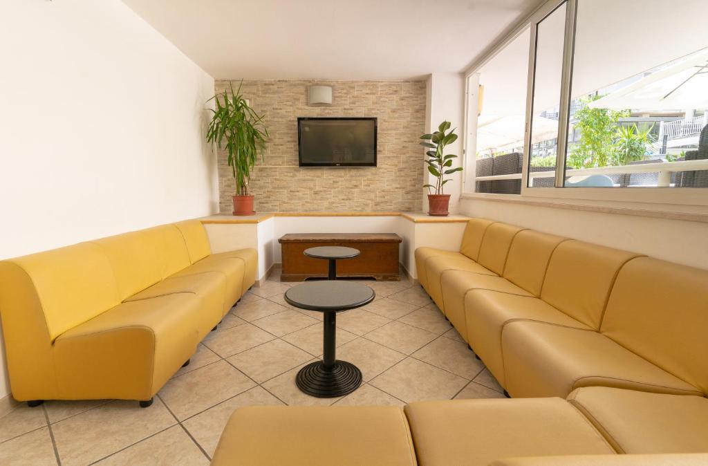 une salle d'attente avec des canapés jaunes et une télévision dans l'établissement Hotel Villa Isola, à Rimini