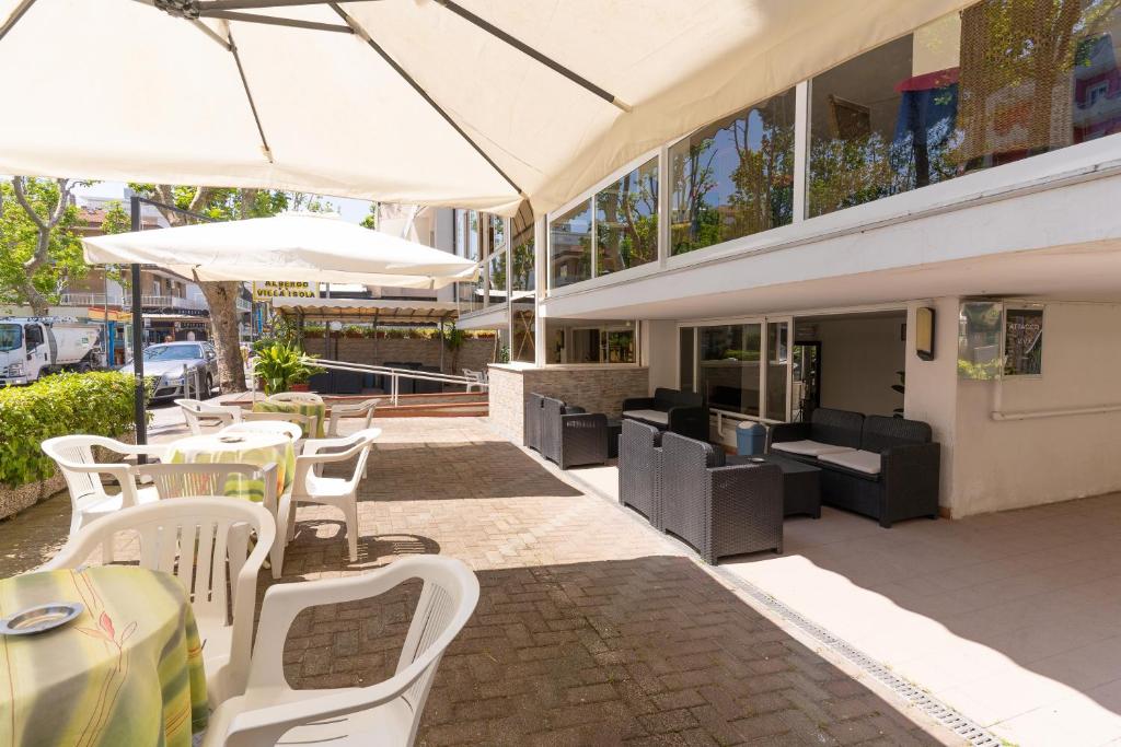 un patio extérieur avec des chaises, des tables et des parasols blancs dans l'établissement Hotel Villa Isola, à Rimini
