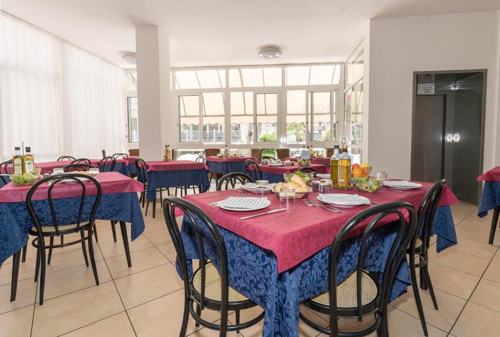 une salle à manger avec des tables et des chaises rouges et bleues dans l'établissement Hotel Villa Isola, à Rimini
