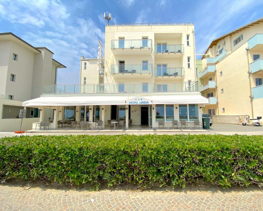 un bâtiment avec une haie devant lui dans l'établissement Hotel Linda, à Caorle