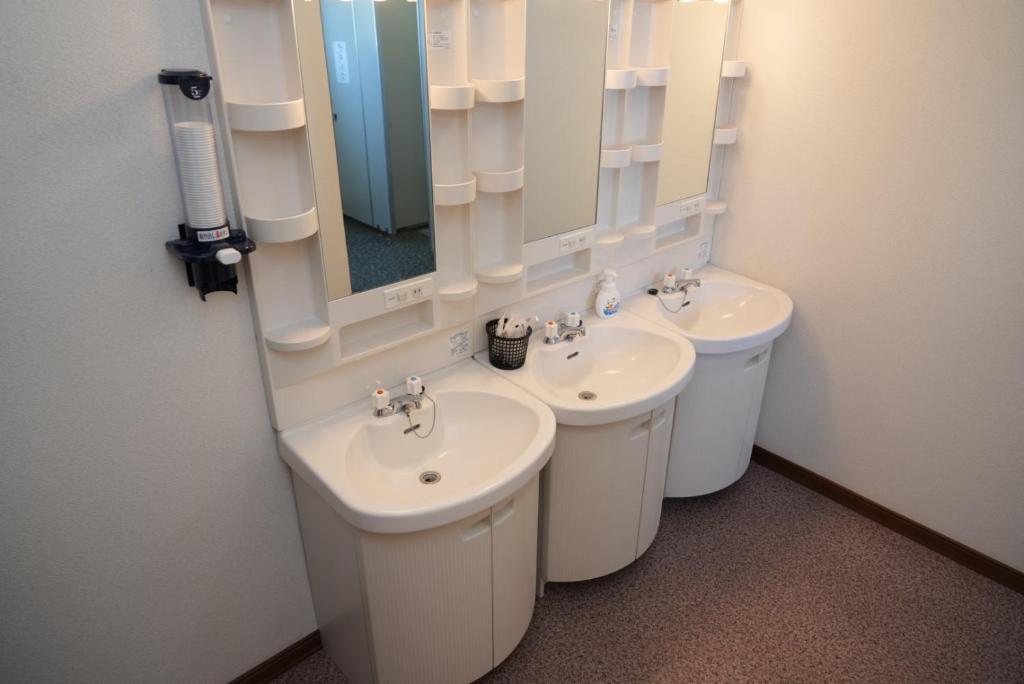 une salle de bain avec deux lavabos et un miroir dans l'établissement Shimanoyado Kamuirishiri, à Rishirifuji 4 autres photos