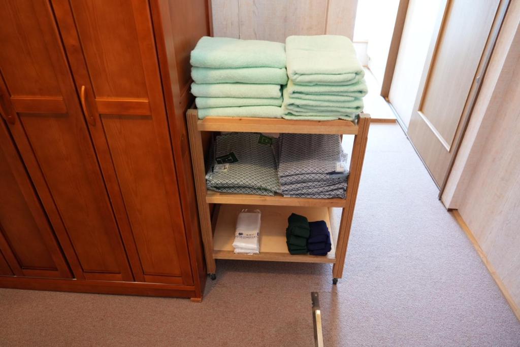 une pile de serviettes sur une étagère dans une pièce dans l'établissement Shimanoyado Kamuirishiri, à Rishirifuji