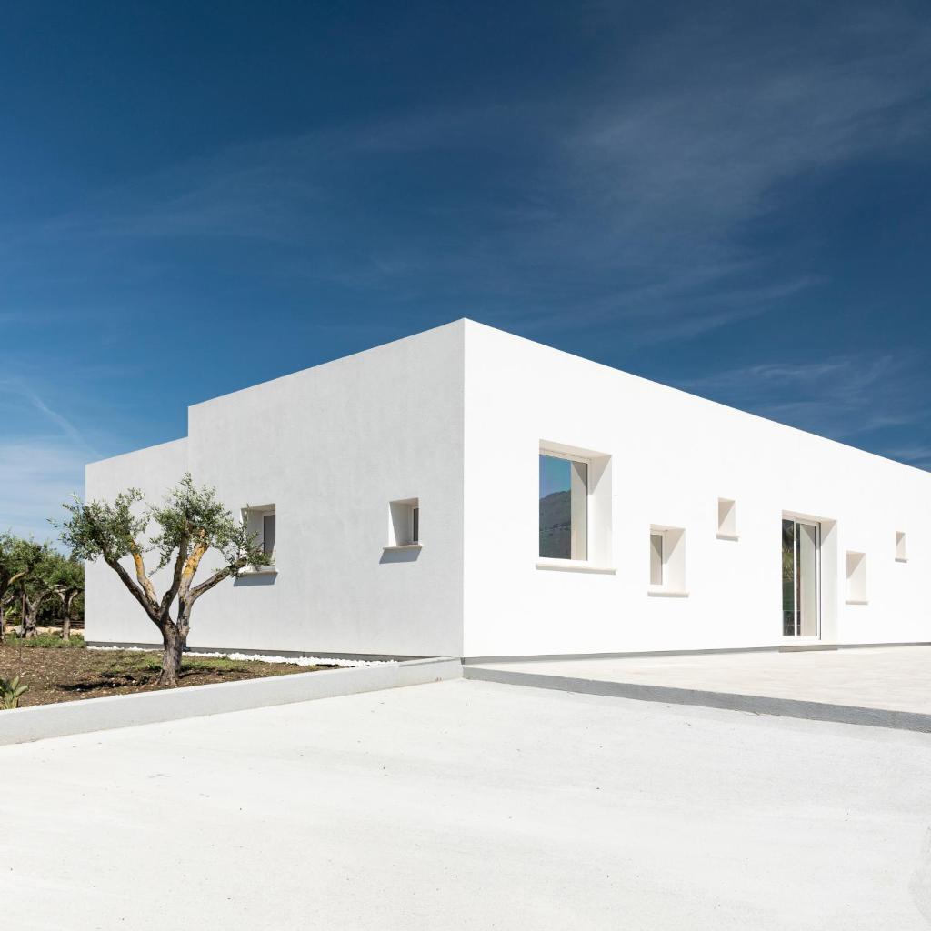 une maison blanche avec un arbre devant dans l'établissement Relais Donna Tana, à Buseto Palizzolo