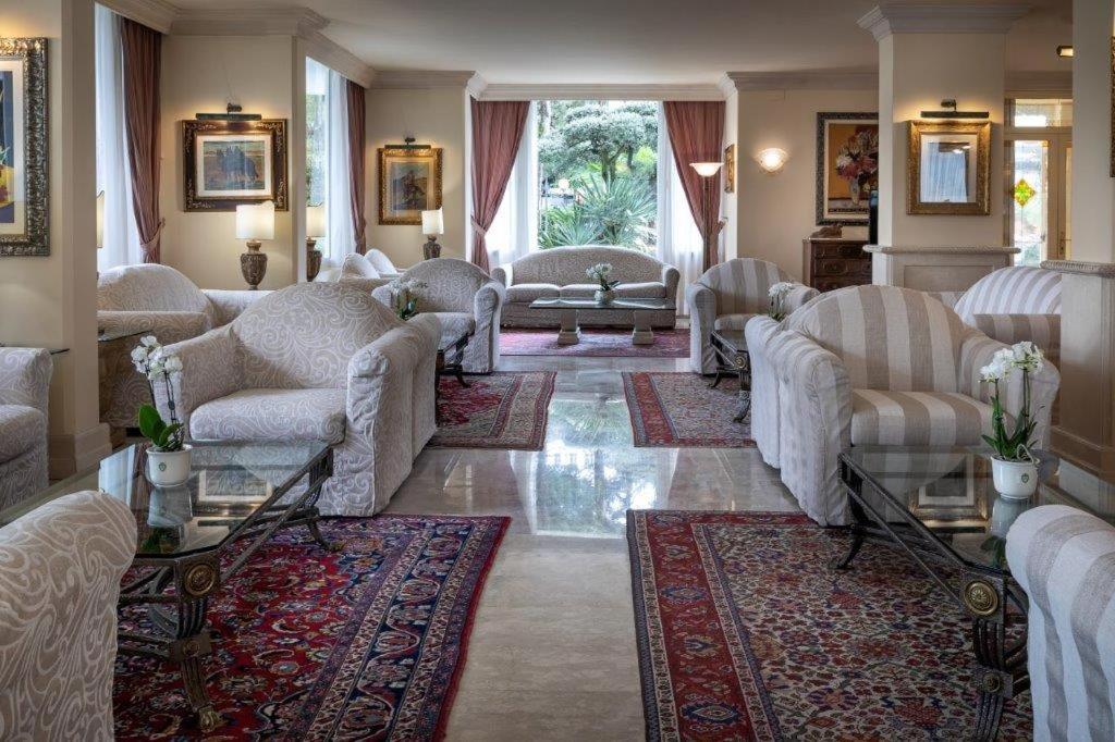 - un salon avec des canapés et des chaises blancs dans l'établissement Hotel Greif, à Lignano Sabbiadoro