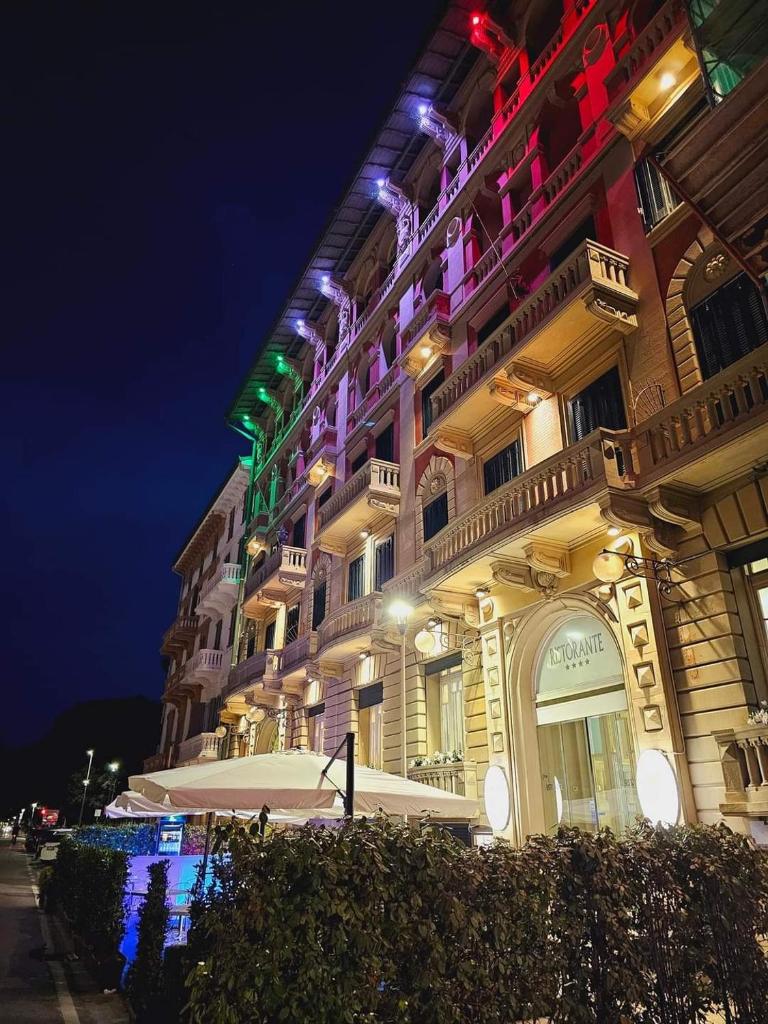 Un grand bâtiment avec des lumières allumées la nuit dans l'établissement Hotel Residence Esplanade, à Viareggio